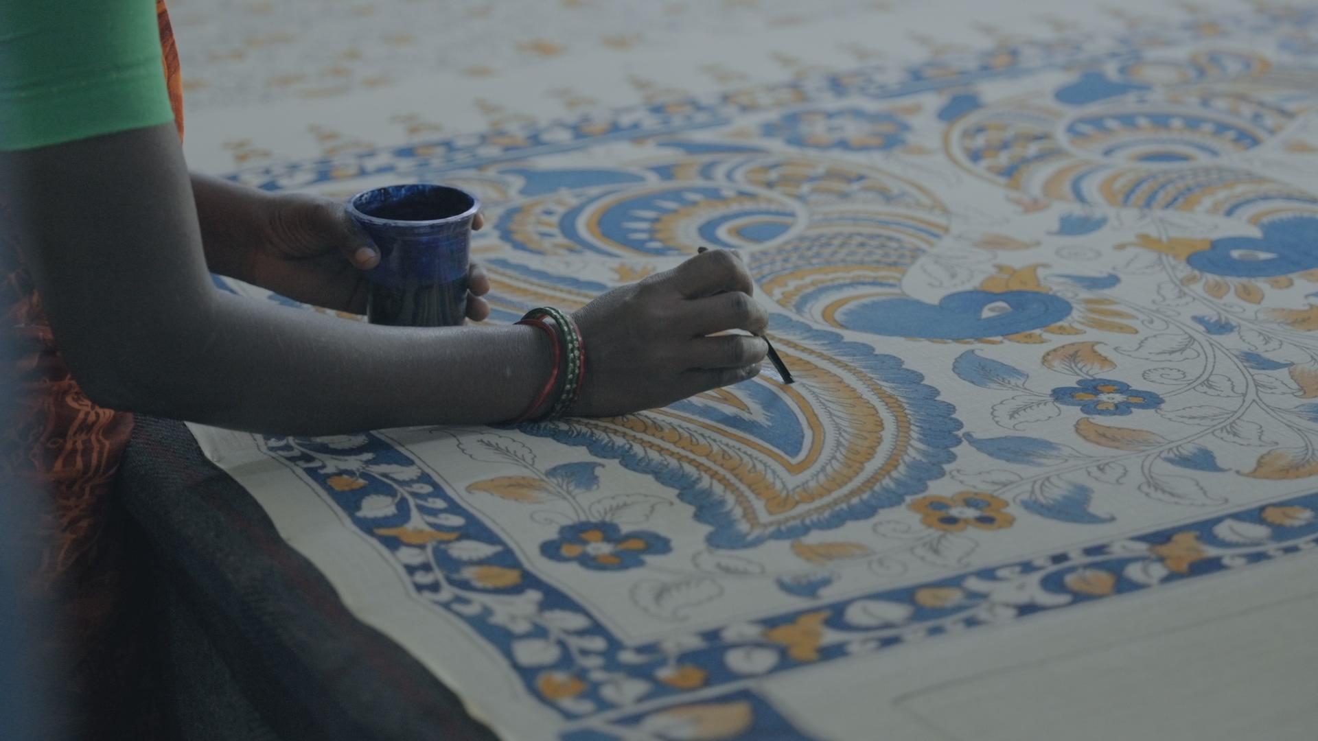 An artisan painting indigo into a kalamkari peacock panel