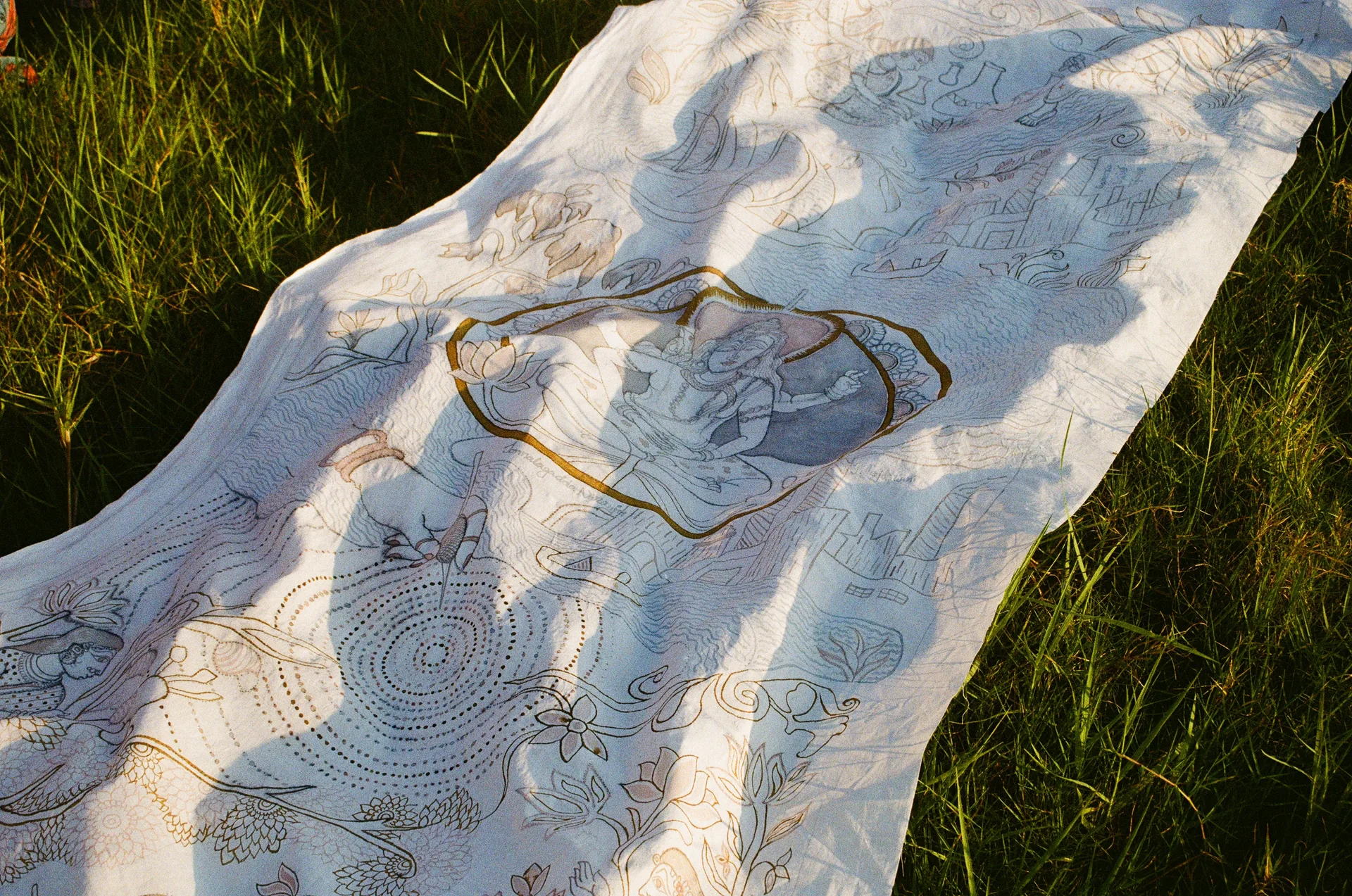 Kalamkari cloth laid across grass at golden hour