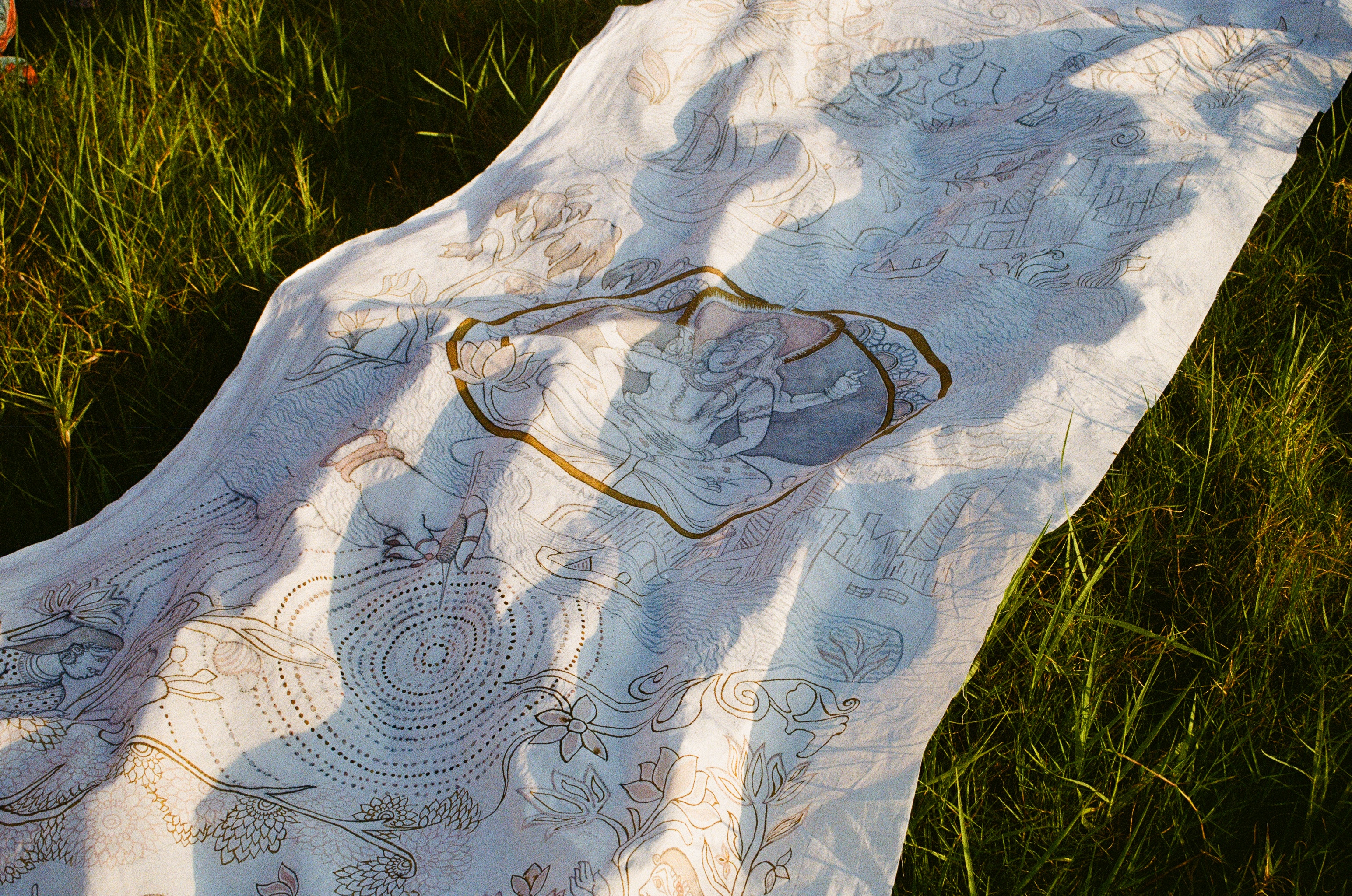 Kalamkari cloth laid across grass at golden hour
